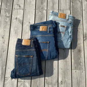 3 par Nudie Jeans i olika blå nyanser - Tre par klassiska jeans från Nudie Jeans i olika blå tvättar – från mörkblå till ljusblå. Alla har orangea sömmar. Två av jeansen är i ”Grim tim” och den sista är i ”Lean dean”. Storlekarna och tvättarna finns i annonserna på min profil. Detta är ett paket så man få det billigare än om man köper alla individuellt!