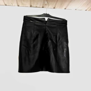 Skinn kjol - Svart skinn kjol med dragkedja bak och resor i midjan.