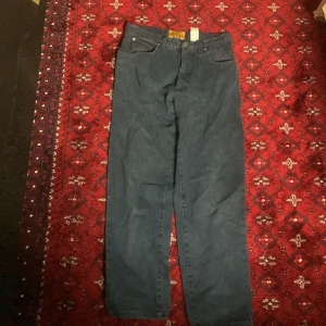 Emporio Armani mörkblå jeans straight - Mörkblå jeans från Emporio Armani med klassisk femficksdesign och straight fit. Snyggt broderad logga på bakfickan och läderpatch i midjan. Jeansen är tillverkade i kraftig denim och har en tidlös look som passar till det mesta. Baggy ! 