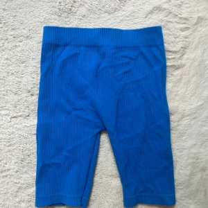 Blå ribbade shorts från Zara - Snygga blå ribbade shorts från Zara med hög midja och stretchig passform. Perfekta för sommaren och riktigt sköna att ha på sig. De är tillverkade i ett mjukt material som sitter tajt och följsamt. Enkla att matcha med en crop top eller oversized t-shirt.