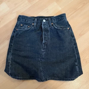 Svart jeanskjol från Levi's -  Svart jeanskjol från Levi's med svart/grå tvätt. Lite osäker på storlek men bord vara en S. 