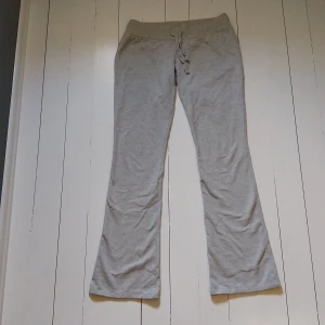 Lågmidjade mjukisbyxor med utsvängda ben - Grå mjukisbyxor från Nelly med bootcut-ben och snörning i midjan. 