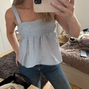 Blåvit randig linnetopp med rosett - Supersöt blåvit randig linnetopp med breda axelband och volangig nederdel. 🤍🤍🤍vet inte var den är ifrån 