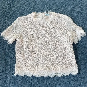Beige spetsblus från Zara❤️ - Supersöt beige spetsblus från Zara Trafaluc med korta ärmar och rund hals. Blusen har vackra spetsdetaljer över hela plagget och en synlig dragkedja i ryggen. Perfekt för dig som gillar romantiska vibes och detaljerad design.