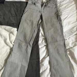 Grå bootcut jeans med raka ben - Snygga grå jeans med bootcut och utsvängda ben. Klassisk femficksmodell med dragkedja och knapp framtill. Jeansen har en ljusgrå tvätt och är tillverkade i mjukt denimtyg. Perfekta för dig som gillar en avslappnad men ändå stilren look. Väldigt lågmidjade. Lite utstretchade vid baksidan. Därför billigt pris 