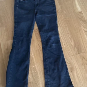 bootcut jeans från Diesel - Säljer ett par svart  jeans från Diesel med klassisk femficksdesign och bootcut-ben. Jeansen har snygga slitningar och en patch med Diesel-logo baktill i midjan. Materialet är mjukt och stretchigt jeans, perfekt för en avslappnad men trendig look.