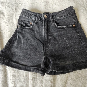 Svarta jeansshorts från Stradivarius oanvända  - Snygga svarta jeansshorts från Stradivarius med hög midja och klassisk femficksdesign. Shortsen har en lätt tvättad look, uppvikta benslut och detaljer i silverfärgad metall. Perfekta för en chill sommarstil.