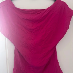 Rosa topp med öppen rygg - Snygg rosa topp i mjukt material med en riktigt djup öppen rygg. Modellen är ärmlös och har en lösare passform upptill. Perfekt för dig som vill sticka ut med en färgstark look och visa lite rygg.