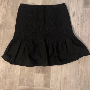 Svart volangkjol - Säljer en svart kjol med smock upptill och volang nertill. Den är köpt några år sedan men har inte kommit till någon användning.