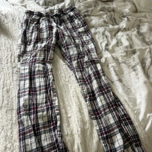 Rutiga pyjamasbyxor  - Säljer ett par rutiga pyjamasbyxor i vitt, svart och vinrött . Byxorna har avslappnad passform och är perfekta för chill dagar hemma.