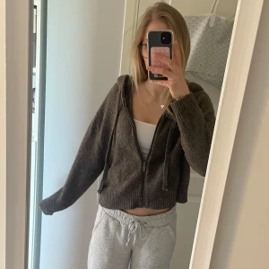 Stickad zip hoodie - Mysig brun stickad hoodie med dragkedja framtill och huva. Modellen är croppad och har långa ärmar. Storlek M, sitter som S🤍🫶🏽