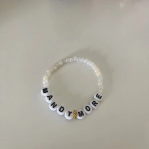 Vitt pärlarmband med text - Säljer ett vitt armband med pärlor och bokstavspärlor som stavar 'MANDY MORE'. Armbandet har en liten gulddetalj mellan orden och är elastiskt för enkel användning. Hov1 inspirerat☀️ 