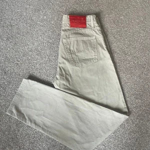 Beige jeans från Jacob Cohën - Snygga beige jeans från Jacob Cohën med klassisk femficksdesign och röd pälsdetalj på bakfickan. Byxorna har rak passform och är perfekt för dig som gillar stilrena och bekväma jeans.
