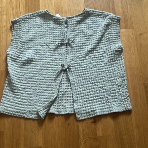 Ljusgrå quiltad väst från Zara med knyt - Säljer en ljusgrå quiltad väst från Zara i storlek 134. Västen har två knyt framtill och är tillverkad i ett mjukt, strukturerat tyg. Perfekt för lager-på-lager och ger en avslappnad look.