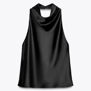 Svart halterneck topp i satin - En svart halterneck topp i satinmaterial från Zara. Toppen har en draperad halsringning och är ärmlös med öppen rygg. Helt ny, aldrig använd. Prislappen sitter kvar. 