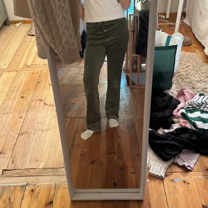 Olivgröna mjukisbyxor från Gina Tricot - Säljer ett par olivgröna mjukisbyxor från Gina Tricot med bootcut-passform. Byxorna har resår i midjan med snörning och två bakfickor. Perfekta för en avslappnad stil och supermjuka i materialet.