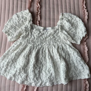 Vit volangblus  - Supersöt vit blus från Gina Tricot med puffiga korta ärmar och volangig struktur. Sitter tajtare längst upp men har en volang som startar typ från mitten vilket gör att den sitter lösare. Blusen har en lös passform och är tillverkad i ett syntetmaterial💞💞