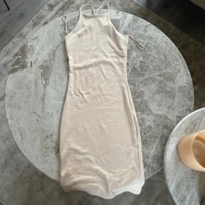 Beige ribbad klänning från Gina Tricot - Säljer en beige ribbad klänning från Gina Tricot med smala axelband och hög halsringning. Storlek XXS, lång, tajt och enkel att styla.