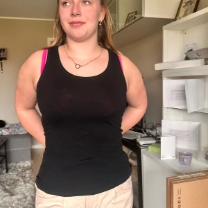 Svart linnetopp - Säljer en enkel svart linnetopp med rund halsringning. Toppen är tight och ärmlös, perfekt för varma dagar eller som lager under andra plagg. Passar till mycket och är ett basplagg i garderoben.