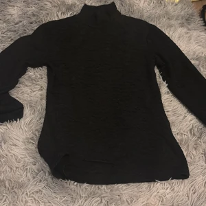 Svart långärmad tröja från Amisu - Säljer en svart långärmad polotröja från Amisu i storlek S. Tröjan har en strukturerad yta och är tillverkad i ett stretchigt material. Perfekt att styla med jeans eller kjol för en snygg look.