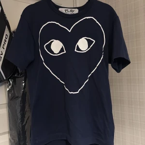 CDG T-shirt - Säljer nu en svinsnygg mörkblå t-shirt från Comme des Garçons Play med det ikoniska hjärtmotivet på bröstet. T-shirten har rund halsringning och är kortärmad. Perfekt nu inför sommaren. Bara att skriva om ni har frågor!
