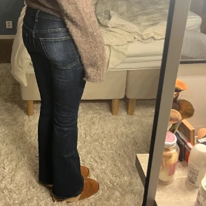 Mörkblå bootcut jeans - Säljer ett par mörkblå jeans med bootcut passform och låg midja från Weekday. Jeansen har klassiska fickor och kontrastsömmar. Perfekta för dig som gillar en tidlös denimlook.💞