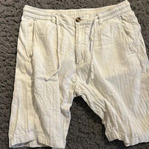Beiga linneshorts från Lindbergh - Säljer ett par beiga shorts från Lindbergh i linne med normal passform. De har snörning i midjan, knappstängning och fickor både fram och bak. Perfekta för varma dagar och en avslappnad stil. Pyttelitet hål vid baken men inget märkt värdigt. Pris kan diskuteras!!