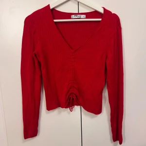 Röd ribbad croppad tröja  - Säljer en röd ribbad tröja från FB Sister Knitwear (New yorker) med v-ringning och långa ärmar. Tröjan är croppad och har snörning framtill som är anpassningsbar. Storlek L men passar mig som bär Xs om man inte vill ha den croppad.