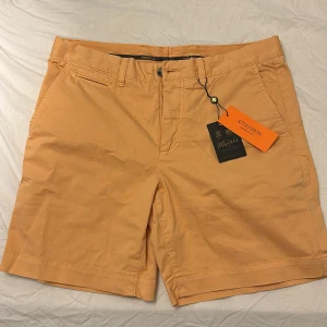 Morris LT Twill Chino Shorts - Snygga orangefärgade shorts från Morris med klassisk design. Shortsen har bälteshällor, knappgylf och två bakfickor med knappar. Perfekta för varma dagar och stilrena outfits. Storlek 32, Aldrig använda🤩 Nypris 1399 kr, som alltid är priset riktigt schysst och inte hugget i sten! Bara att skriva om ni undrar över något🤩