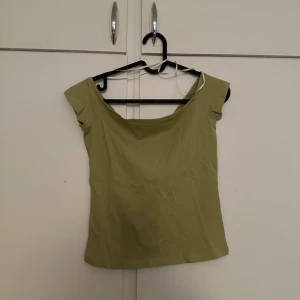 Ljusgrön off shoulder topp - Säljer en ljusgrön off shoulder topp med breda axelband och rundad halsringning. Toppen har en enkel och stilren design, perfekt att matcha med jeans eller kjol.