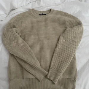 Beige stickad tröja från J.Lindeberg - Säljer en beige stickad tröja från J.Lindeberg i storlek M. Tröjan har ett diskret rutmönster och ribbade muddar vid ärmslut, hals och nederkant. Perfekt för lager-på-lager under kyligare dagar. Använd 2 gånger, storlek M men kan passa L, priset kan diskuteras, original priset ligger på 1500kr köpt på volt.