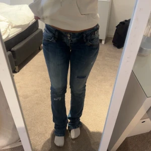 Blå jeansbyxor från LTB - Säljer ett par klassiska blå jeansbyxor från LIB med snygga slitningar och kontrastsömmar. Byxorna har normal passform, fem fickor och låg midja. Perfekta för en avslappnad stil. Storlek 28/32