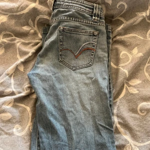 Blåa low jeansboutcut från Teddy's Hyper - Klassiska blå jeansbyxor från Teddy's Hyper med fem fickor och snygga kontrastsömmar. Bakfickan har dekorativ broderad detalj i vitt och orange. Perfekta för en avslappnad stil.               Är från 2010 som nya!