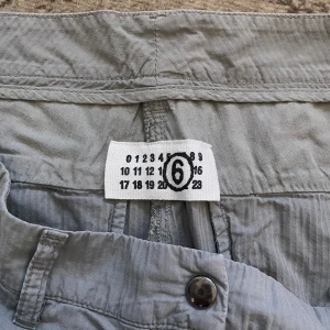 Ljusgrå shorts från Martin Margiela - Säljer ett par ljusgrå shorts från Martin Margiela. De har en ganska lång passform, knapp och dragkedja framtill samt fickor på sidorna och baktill. Tillverkade i Italien. Inte sett liknande någonstans.