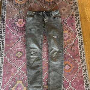 Gråa Slim/Glenn jeans Jack & Jones - Gråa Slim/Glenn jeans från Jack & Jones. Aldrig använda då dem var för små för mig. Köpta på Zalando. Rätt så ovanliga finns inte kvar att köpa längre. Väldigt snygga med slitningar, storlek 34/34. 
