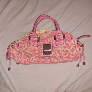 Rosa och beige handväska från Guess - Säljer en snygg handväska från Guess i rosa och beige med leopardmönster. Väskan har silverfärgade metalldetaljer, dubbla handtag och dragkedja upptill. Insidan har ett mönstrat foder och en innerficka med dragkedja. Osäker på äkthet. 