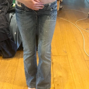 Blå bootcut jeansbyxor från Miss Me - Säljer ett par blå bootcut jeans från Miss Me med slitningar och dekorativa bakfickor med broderi och detaljer. Jeansen har låg midja och klassisk femficksdesign. Perfekta för dig som gillar en unik och trendig denimstil. Midjemått:34. Innerben:74