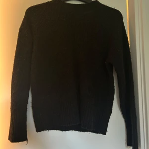 Svart stickad tröja från Lindex - Mysig svart stickad tröja från Lindex. Klassisk modell med rund halsringning och långa ärmar. Perfekt för kyligare dagar och enkel att matcha med olika outfits.