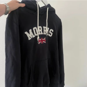 Morris hoodie  - Säljer denna riktigt populära Morris hoodie i bra skick. Den är sparsamt använd. Den är mörkblå och har de populära märket på framsidan. Hoodie har även metal detaljer på snörena där det står morrris på. Vid fler frågor är det bara att höra av sig. 