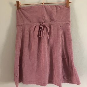 Rosa tubtopp  - En söt rosa tubtopp med knytband i midjan . Toppen har en mjuk och bekväm känsla, perfekt för varmare dagar. Enkel design med diskreta sömdetaljer längs sidorna.