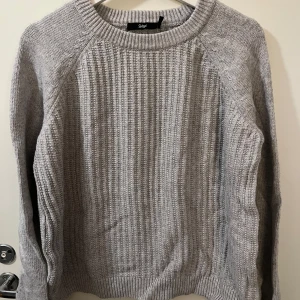 Grå stickad tröja från Sportsgirl - Säljer en klassisk grå stickad tröja från Sportsgirl. Tröjan har rund halsringning och ribbad struktur både på ärmar och kropp. .