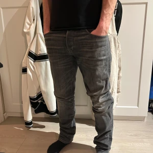 Grå jeansbyxor herr - Säljer ett par grå jeansbyxor med klassisk femficksdesign och rak passform. Byxorna har normal midja och är tillverkade i denim. Perfekta för dig som gillar en enkel och stilren look.
