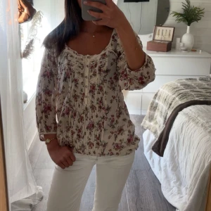Blommig blus med spetsdetaljer - Romantisk blommig blus med spetsdetaljer och knappar framtill. Blusen har trekvartsärm och ett löst, luftigt fall. Perfekt för vår och sommar☀️🤍🫧🌊
