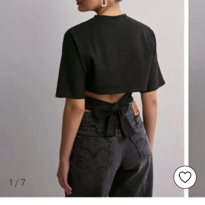 Svart croppad t-shirt med knyt i ryggen - Säljer den här jätte fina tröjan från Nelly, jätte bra skick, använd 3 gånger, skickar bild ifall man undrar något💗