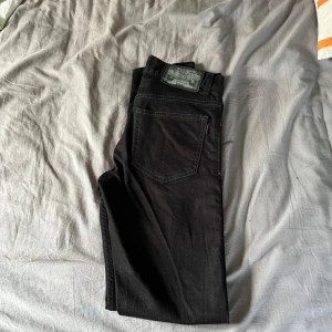 Svarta jeansbyxor från Crocker - Säljer ett par svarta jeansbyxor från Crocker med klassisk femficksdesign och raka ben. Byxorna har en tydlig Crocker-lapp bak i midjan och röda Crocker-detaljen på bakfickan. Perfekta för en stilren och enkel look.