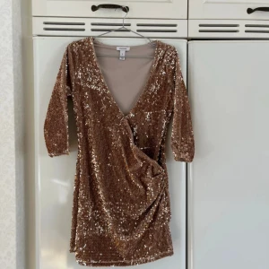 Glittrig klänning från Oneness - Mkt bra skick, skriver att det kan finnas ng paljett som ramlat av men hittar ingen! Säljer en glittrig klänning från Oneness i storlek S. Klänningen har en v-ringad design med trekvartsärm och är täckt av paljetter i en vacker champagnefärg. Perfekt för en festlig kväll!