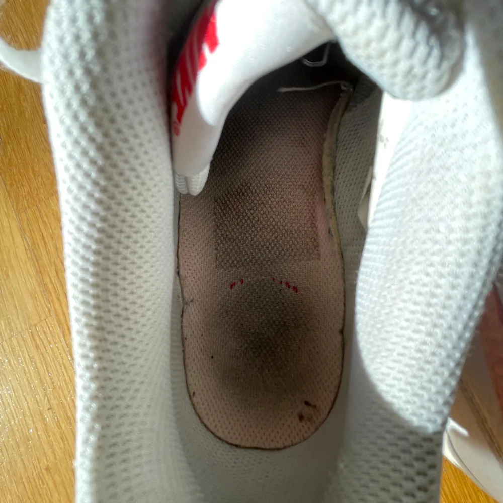 Säljer ett par vita Nike sneakers med rosa detaljer och snörning. Skorna har en klassisk design med perforeringar på tån för ventilation. Perfekta för en avslappnad stil.. Kengät.