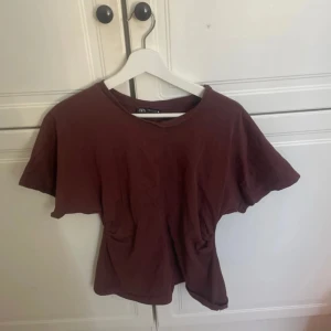 Brun t-shirt från Zara - Säljer en brun t-shirt från Zara med korta ärmar. Perfekt för en avslappnad stil. Tillverkad i ett mjukt material som känns skönt mot huden.figursydd.