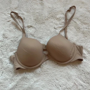 Beige bh från Calvin Klein - Säljer en stilren beige bh från Calvin Klein. Den har justerbara axelband och en slät design som ger en bekväm passform. Perfekt för vardagsbruk. Hör av dig vid intresse!