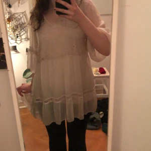 Beige blus med spetsdetaljer - Säljer en luftig beige blus med v-ringning och spetsdetaljer. Blusen har trekvartsärmar och volangdetaljer som ger en romantisk känsla. Perfekt för en stilren look. Älskar denna tröjan så mycket men behöver pengar 😿